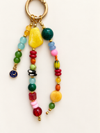 A colorful beaded keychain with a gold-tone split ring, featuring various round and textured beads in yellow, green, blue, pink, red, orange, and black, along with a small blue enamel charm.