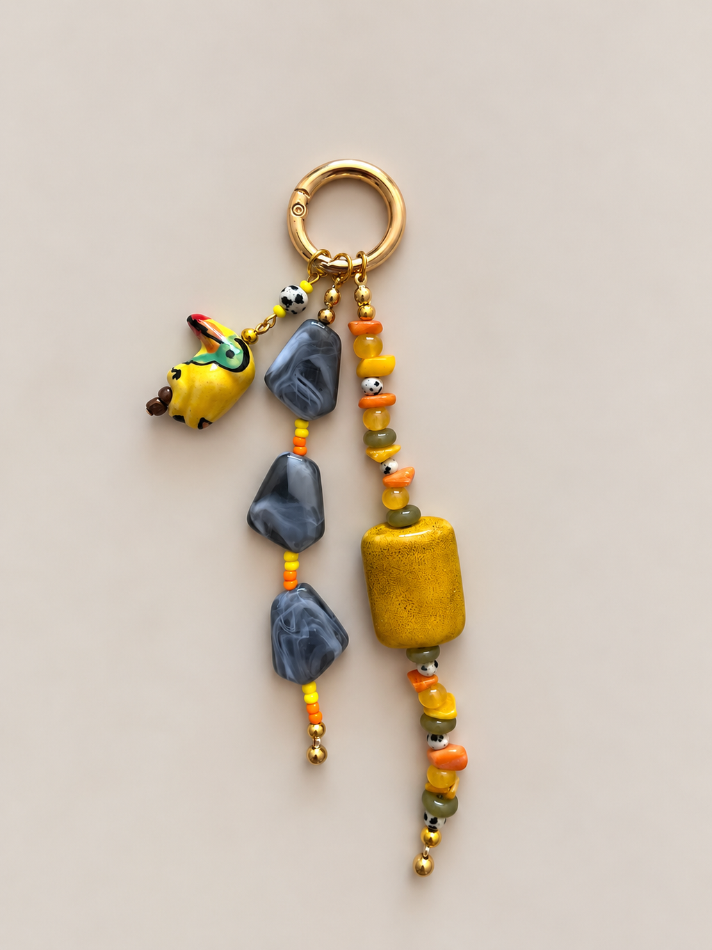Beaded bag charm with yellow, orange, gray and black beads, three dangling strands and a small animal figure.